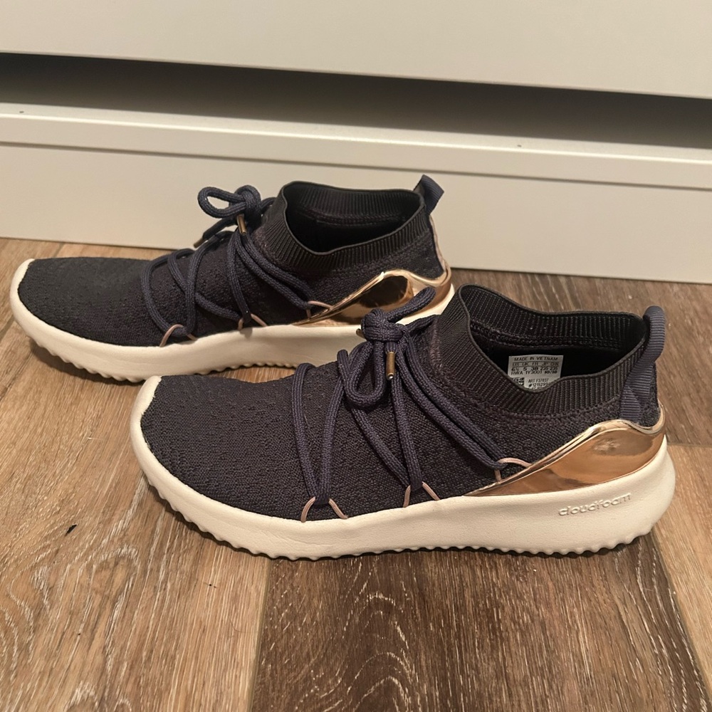 Adidas women’s dark gray and gold sneakers.